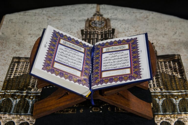 An open Quran on a wooden stand atop a prayer rug, emphasizing Islamic faith.